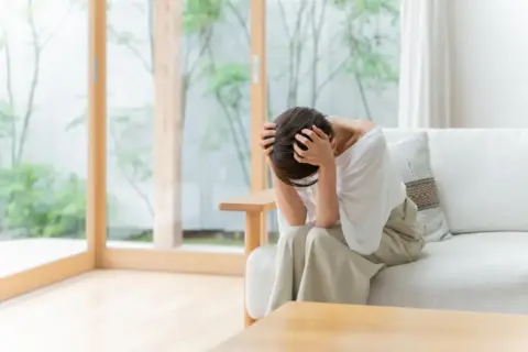 頭痛で頭を抱える女性