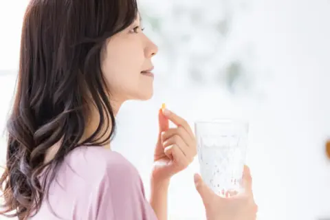 サプリメントを飲む女性