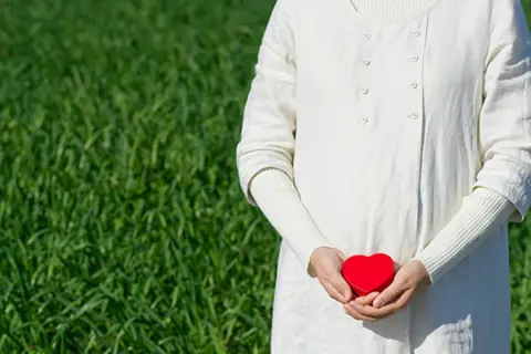 お腹に赤いハートを添えた女性
