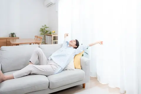 ソファで伸びをする女性