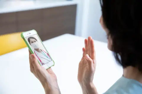 スマホでオンライン診察を受ける女性