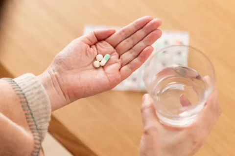 薬を飲む人の手とコップ