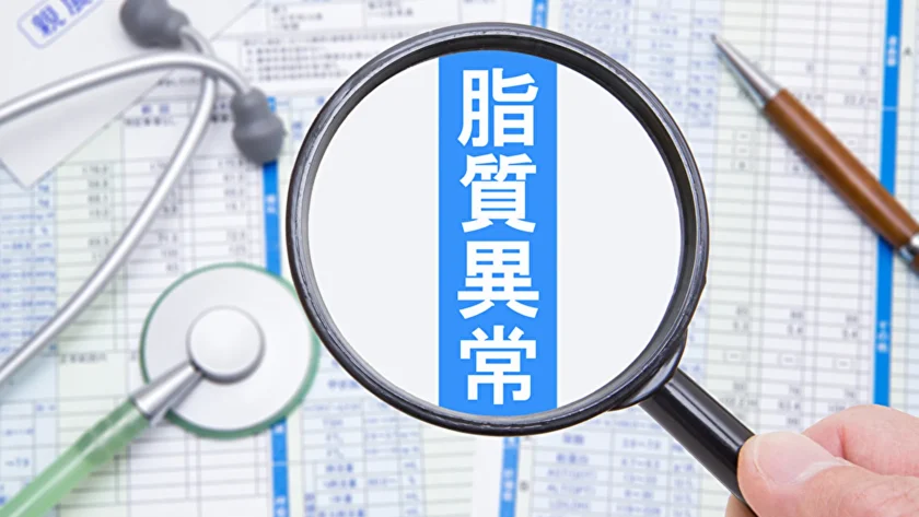 脂質異常症の字を虫眼鏡で拡大している人の手