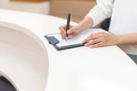 病院の受付で問診票を記入する患者さん 受診の目安