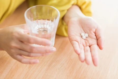 薬を手にもって今から飲む患者さん　市販薬と処方薬の違いについて考えている