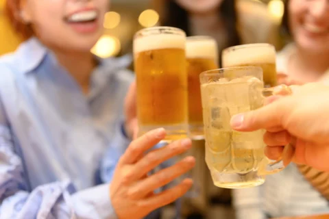 飲み会でお酒を手に持ち乾杯する人たち