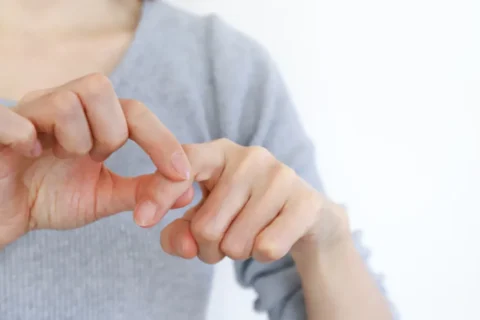指の関節をつかむ女性の手