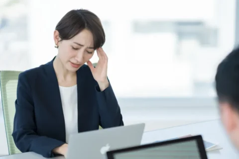 仕事中に片頭痛の症状苦しむ女性
