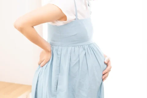 大きなお腹で腰に負担がかかっている妊婦