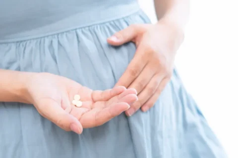 手のひらに薬をのせた妊婦