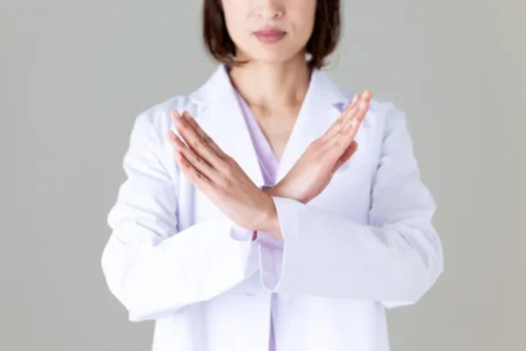 手でバツをつくる女性医師