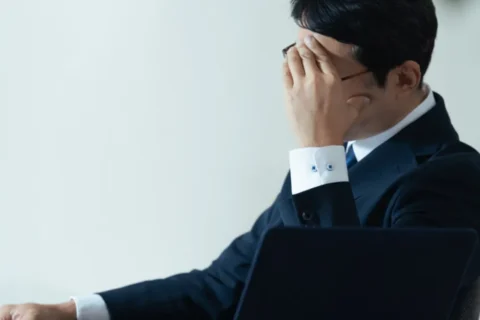 寝不足で頭を抱えるサラリーマン