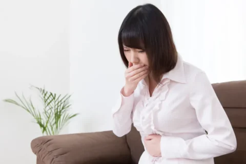 吐き気や胃のむかつきを感じる女性