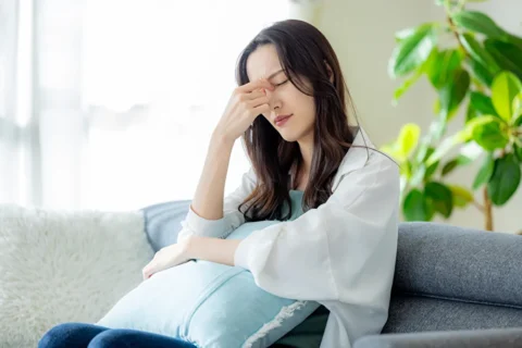 頭痛やだるさを感じてい休んでいる女性
