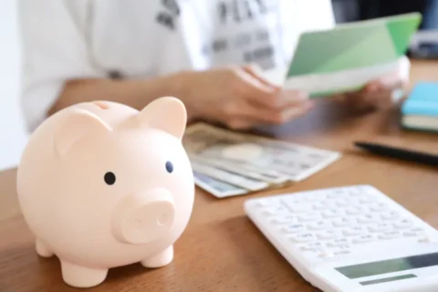 豚の貯金箱とお金を計算する女性