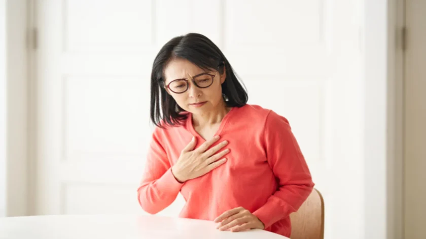 動悸を感じ胸を抑えている女性