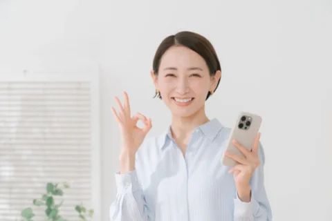 スマホを持ってOKサインをしている女性
