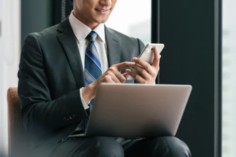 PCを膝に乗せスマホを操作する男性