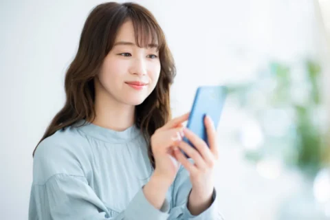 スマホでオンライン診療の予約をしている女性