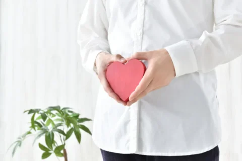 下腹部前でハートのオブジェを持っている女性